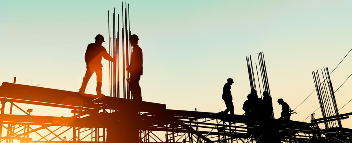 Silhouetted workers constructing a building